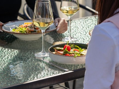 Stolik na tarasie z winem i podanymi daniami w Za Bunkrem 2.0, rebranding kompleksu hospitality przez Frame 43